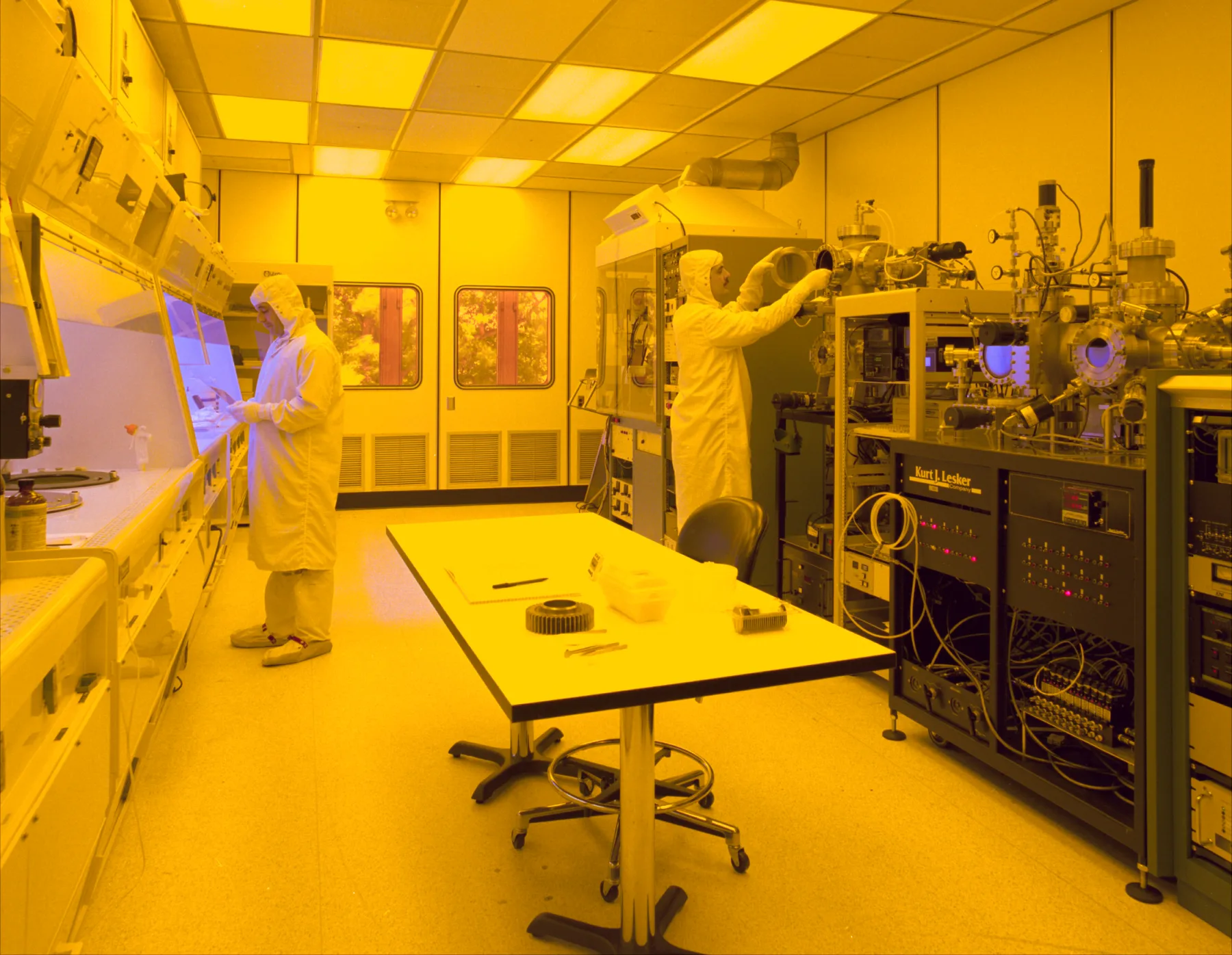 Engineers working with semiconductor fabrication equipment in a cleanroom